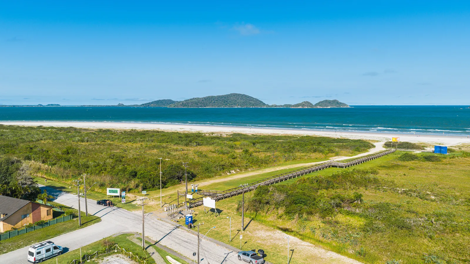 Restinga, passarela e praia com a Ilha do Mel ao fundo, em Pontal do Paraná
